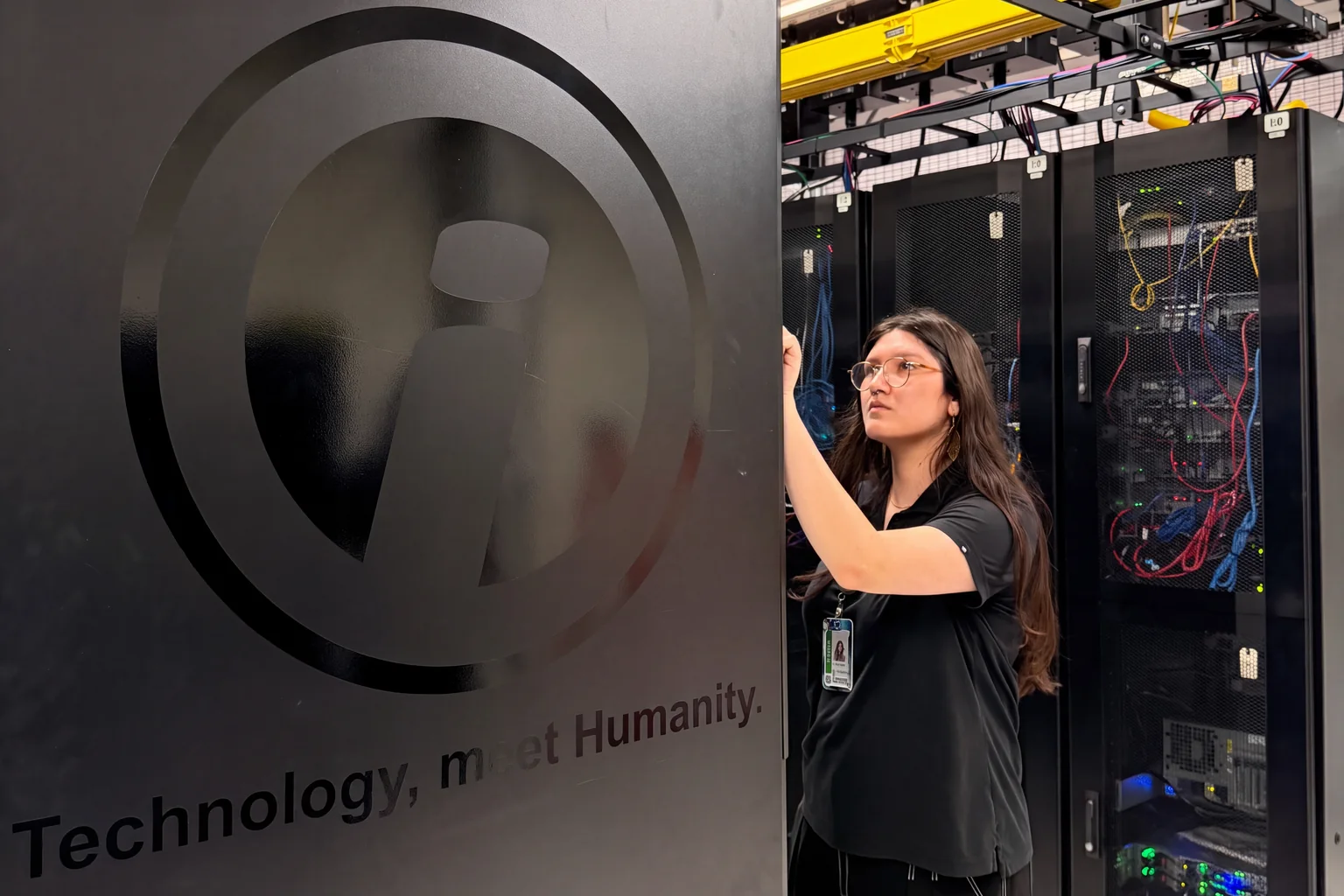 An Opus Interactive engineer working beside a branded cabinet in a data hall.