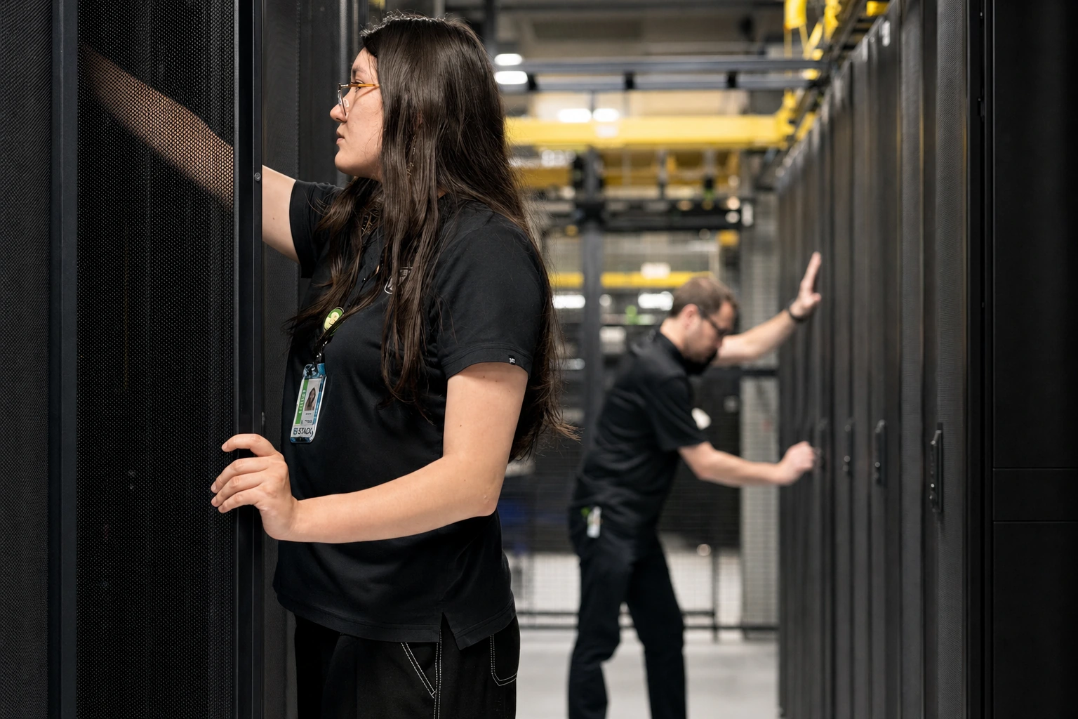 Opus Interactive engineers working along a data hall aisle of Tier III+ cabinets.