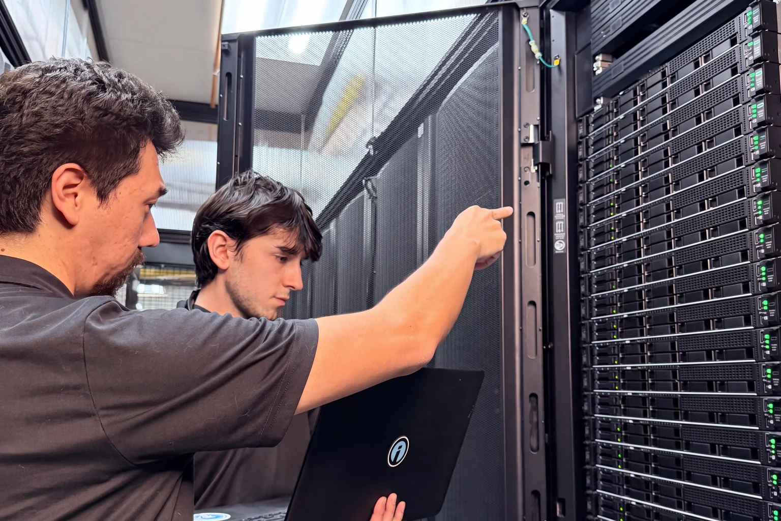 Two Opus Interactive engineers checking a switch at an open rack.