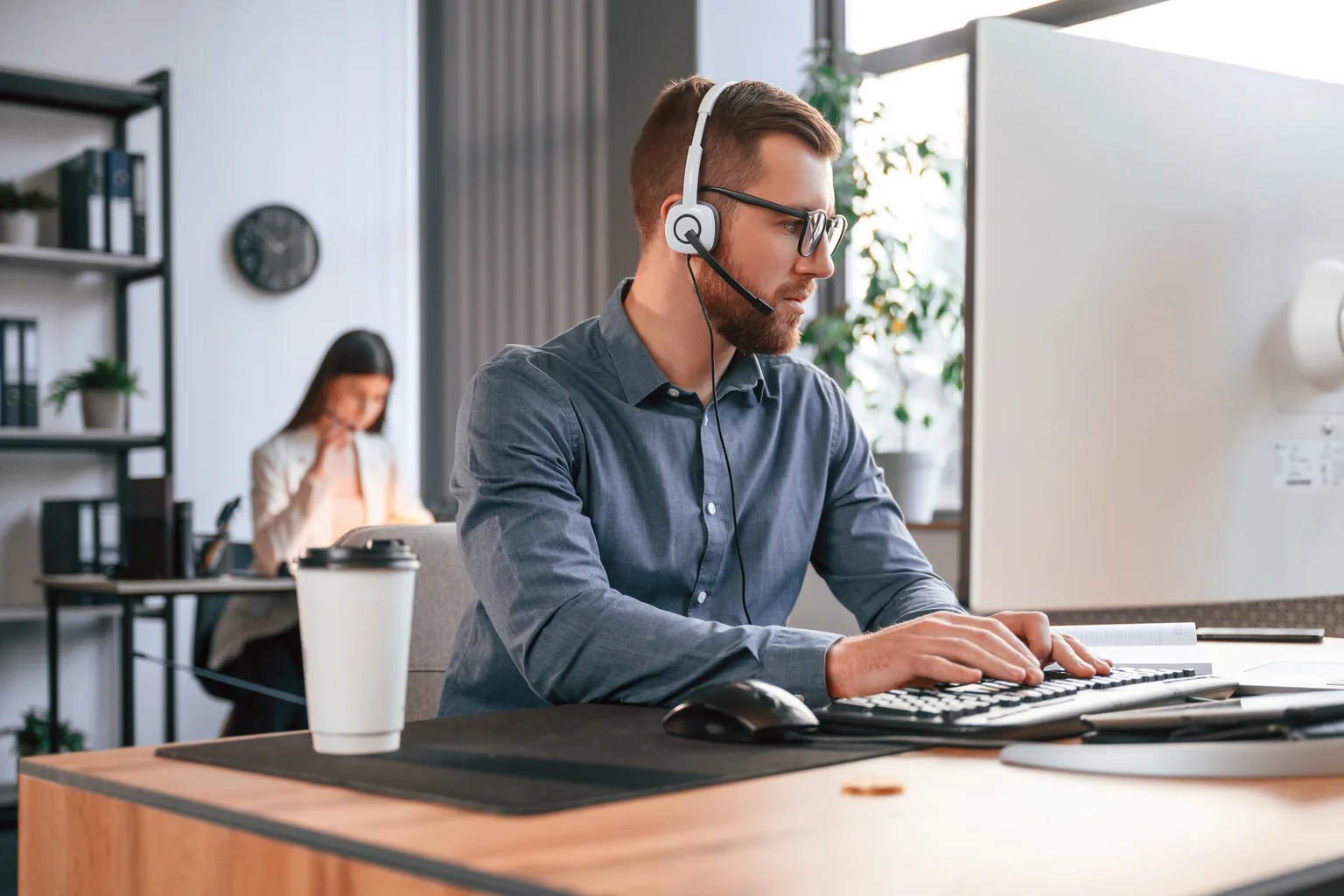 An employee working at a virtual desktop workstation in a bright office.